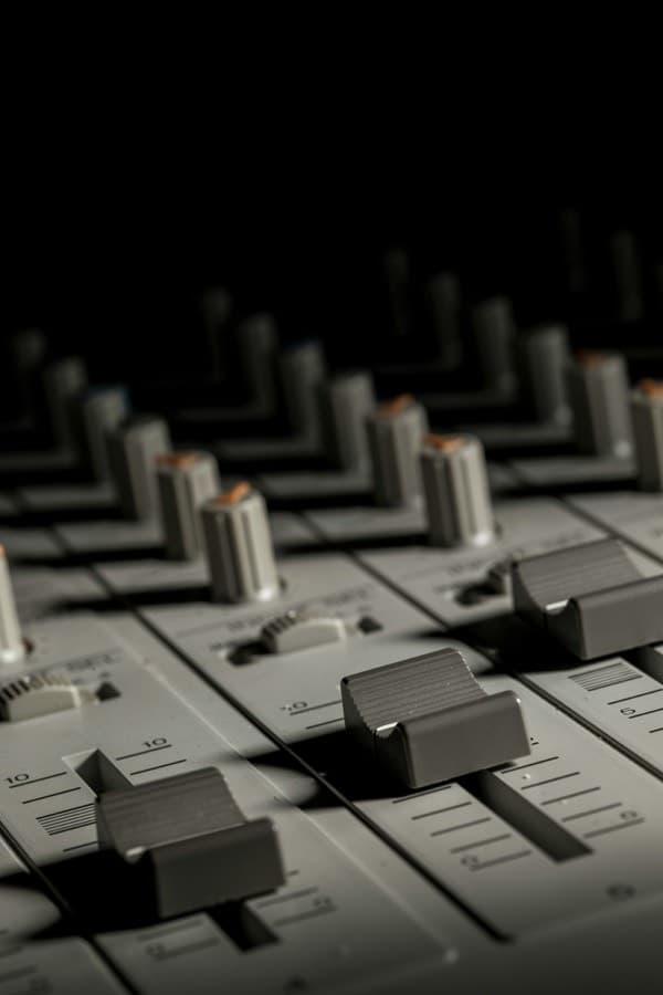 Mixing console under studio light, faders and knobs in close-up